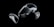 A set of virtual reality equipment, including a headset and two handheld controllers, displayed against a black background. The headset has a sleek, modern design with a glossy surface, while the controllers feature several buttons and joysticks.