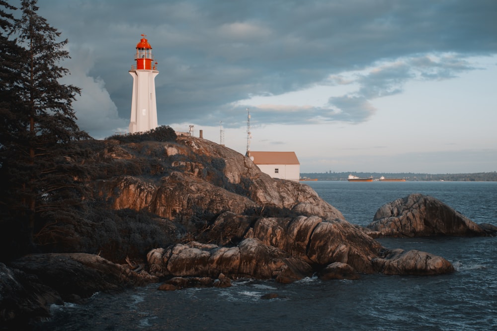 a white and red lighthouse on a rocky shore