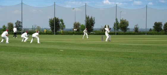 A lively cricket match in progress with doctors in white coats cheering from the sidelines.