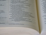 A close-up view of an open book displaying biblical text. The text includes verses numbered 19 through 22, discussing various religious themes. The pages are slightly curved, and the text is in a formal, serif font with a verse number reference.
