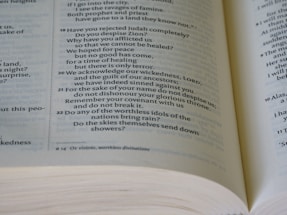 A close-up view of an open book displaying biblical text. The text includes verses numbered 19 through 22, discussing various religious themes. The pages are slightly curved, and the text is in a formal, serif font with a verse number reference.
