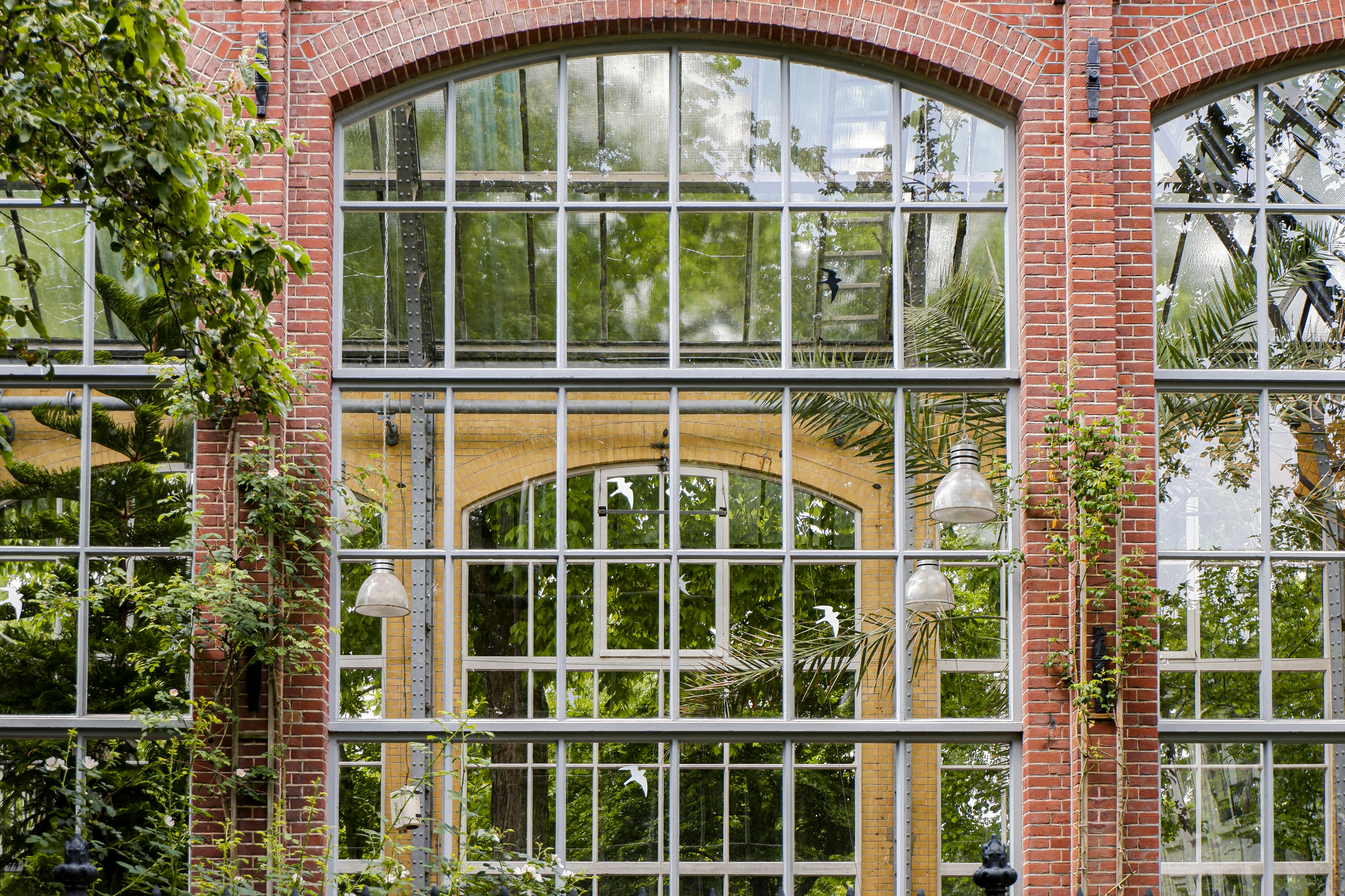 Ein Backsteingebäude mit vielen Fenstern und Pflanzen