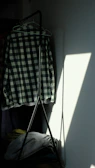 Subtle shadow play on a monochrome shirt hanging gently from a sleek black hanger.