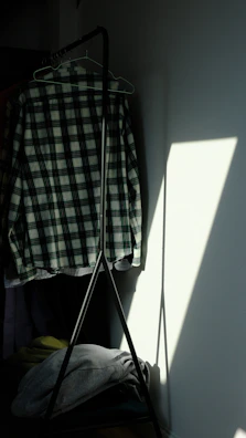 Subtle shadow play on a monochrome shirt hanging gently from a sleek black hanger.