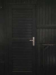 Close-up of a matte black Stilex steel security door with brushed silver accents, highlighting the sleek handle and reinforced frame.