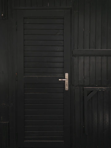 Close-up of a matte black Stilex steel security door with brushed silver accents, highlighting the sleek handle and reinforced frame.