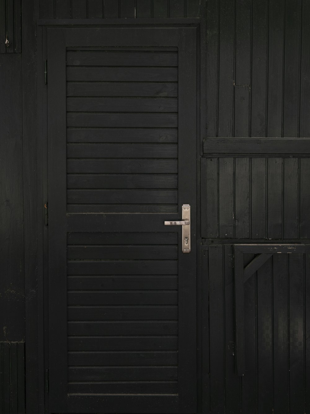 a black wooden door with a metal handle