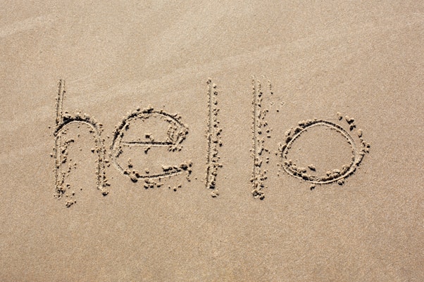 the word hello written in the sand on a beach