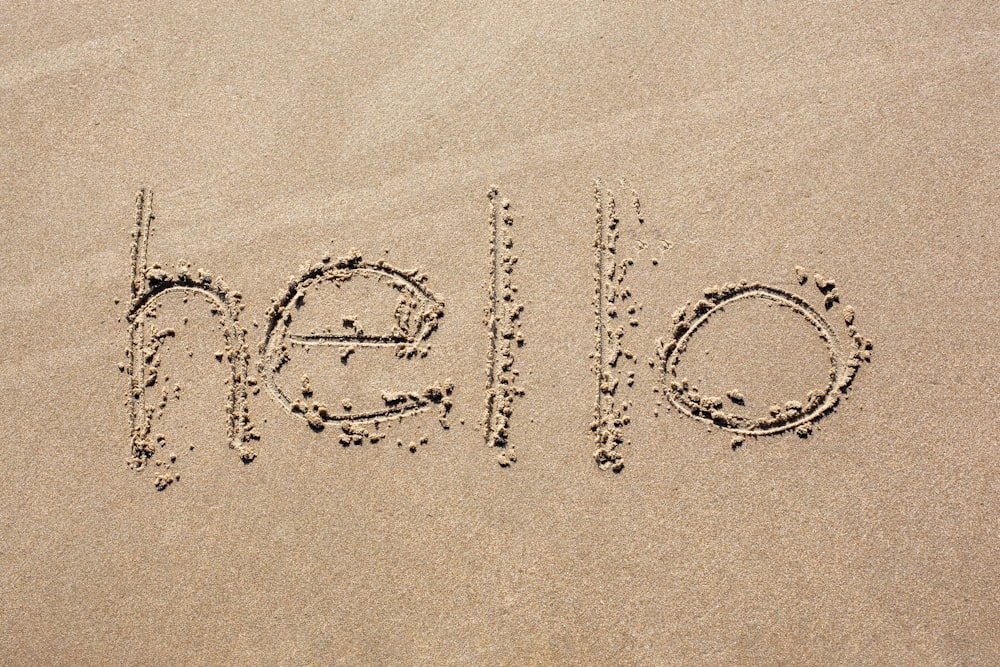 the word hello written in the sand on a beach