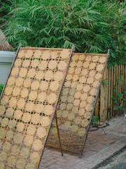 Seagrass mats drying under the warm Asian sun on a wooden rack.