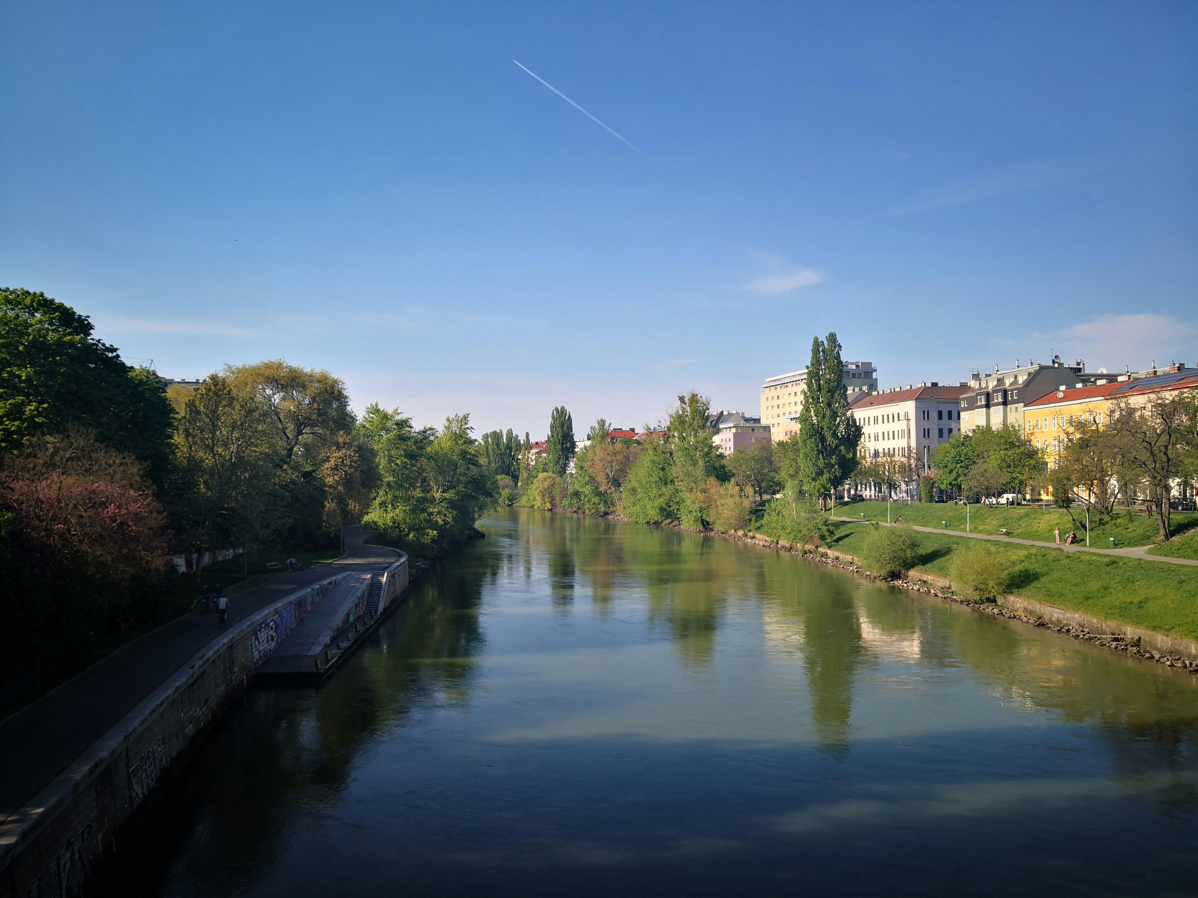 River with clear water and green banks, serene natural landscape, bright daylight, clean environment