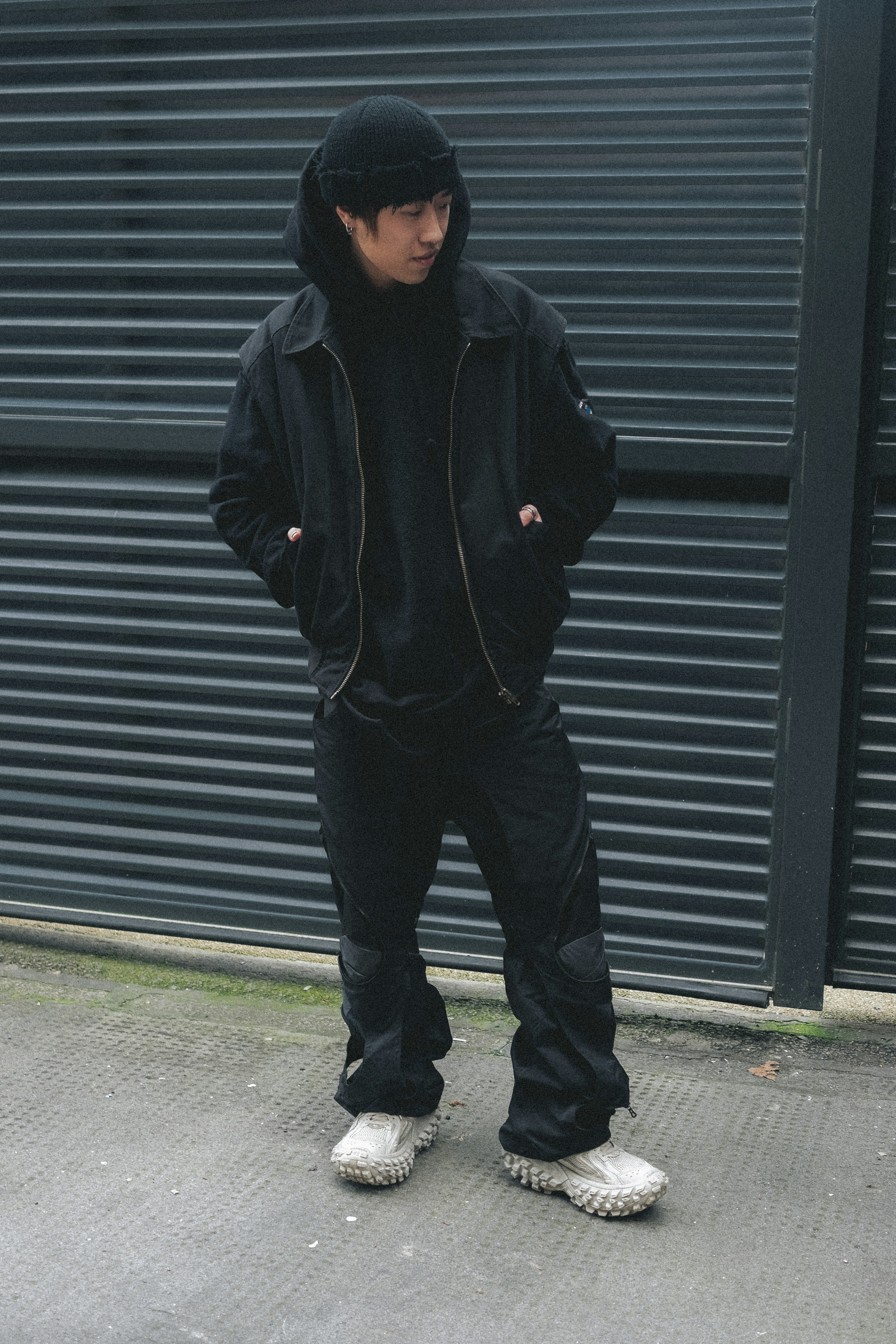 A man standing on a sidewalk wearing a black hoodie photo – Free London