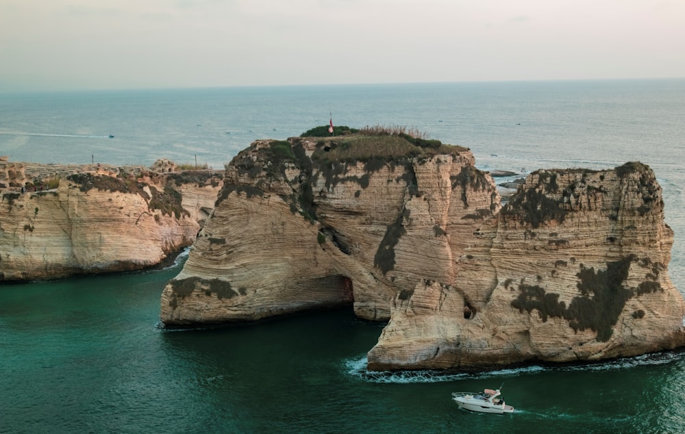 Una barca è in acqua vicino a una grande formazione rocciosa