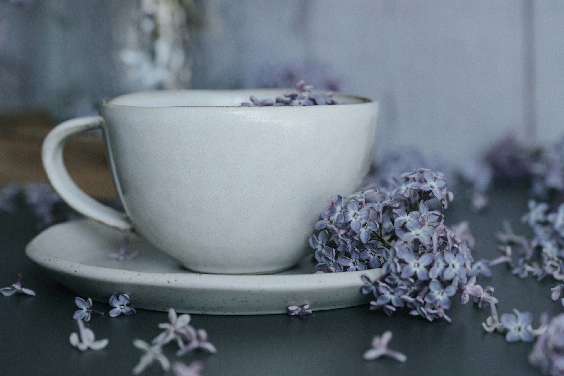 a white cup and saucer filled with purple flowers