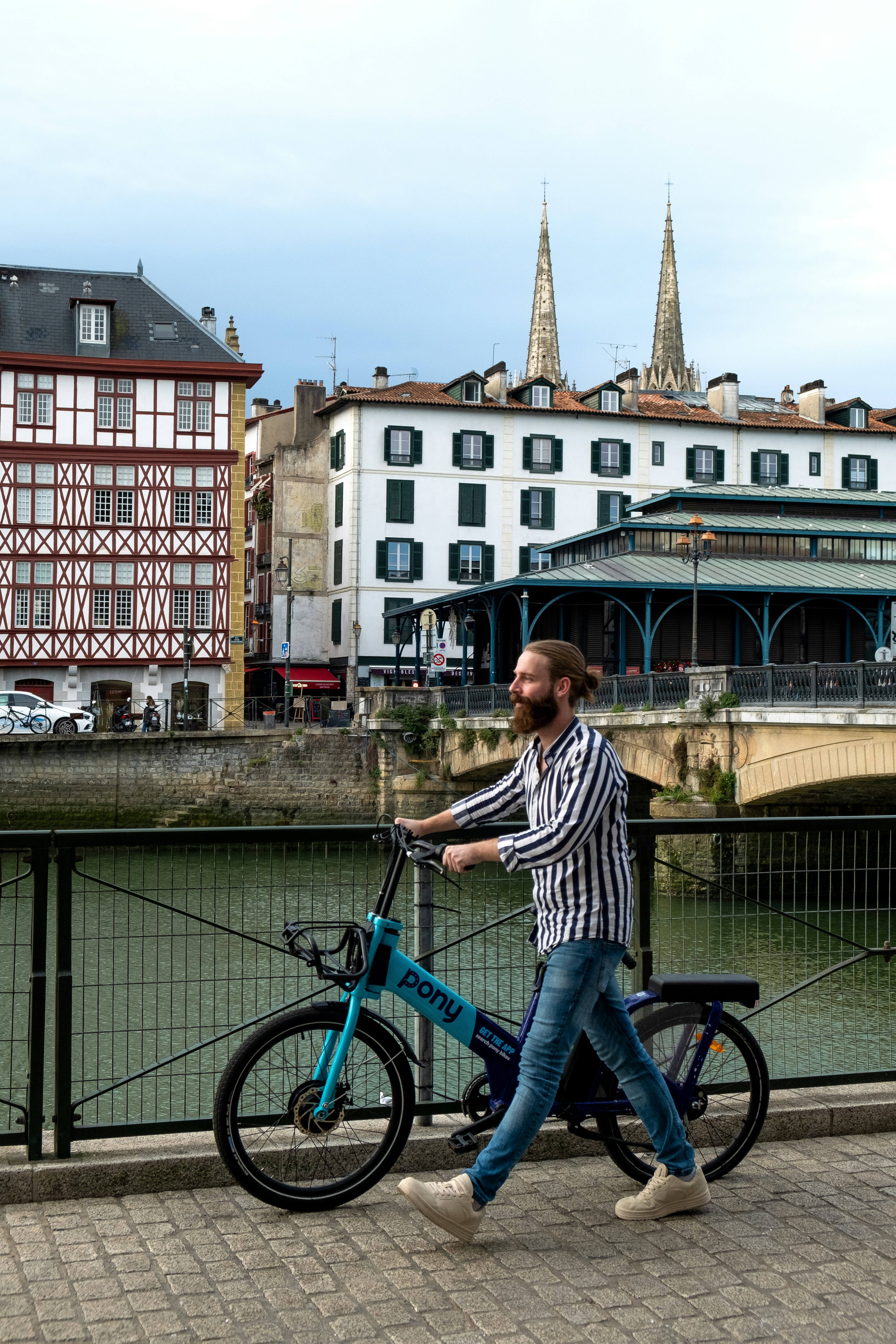 a man walking a bike across a bridge