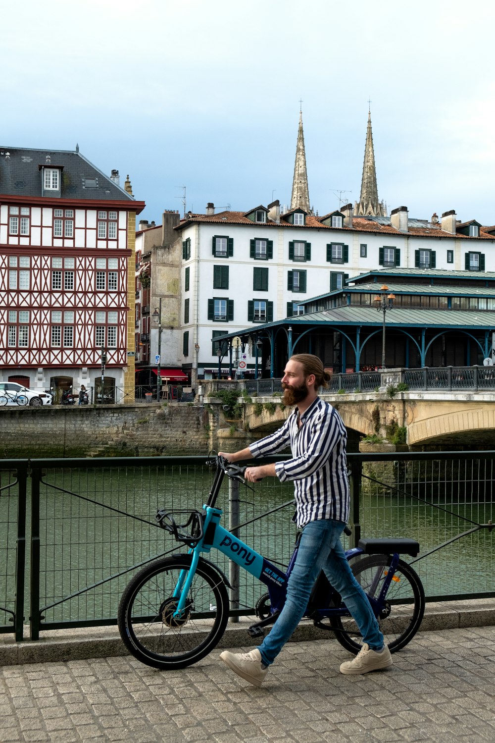 a man walking a bike across a bridge