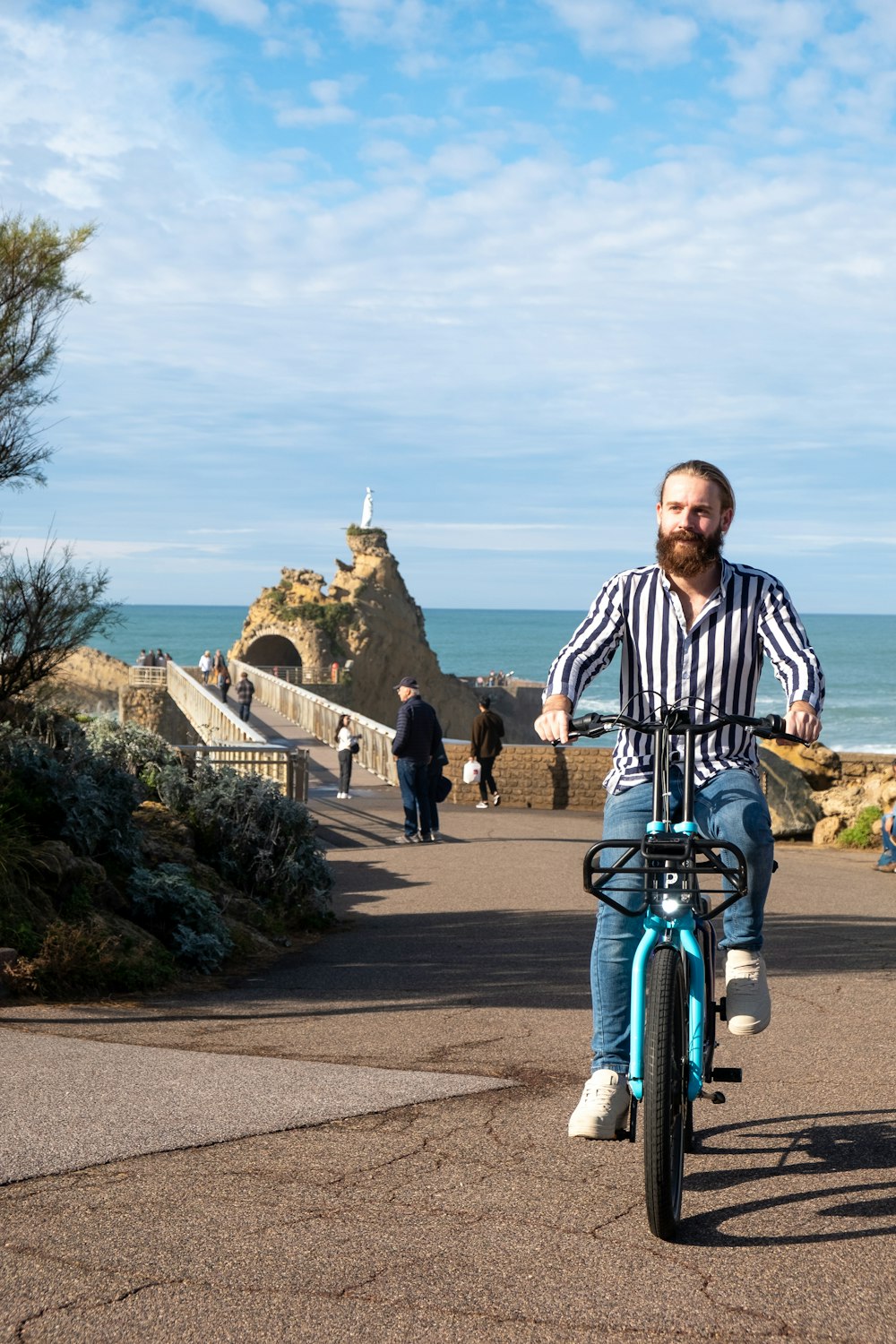 a man riding a bike down a road next to the ocean