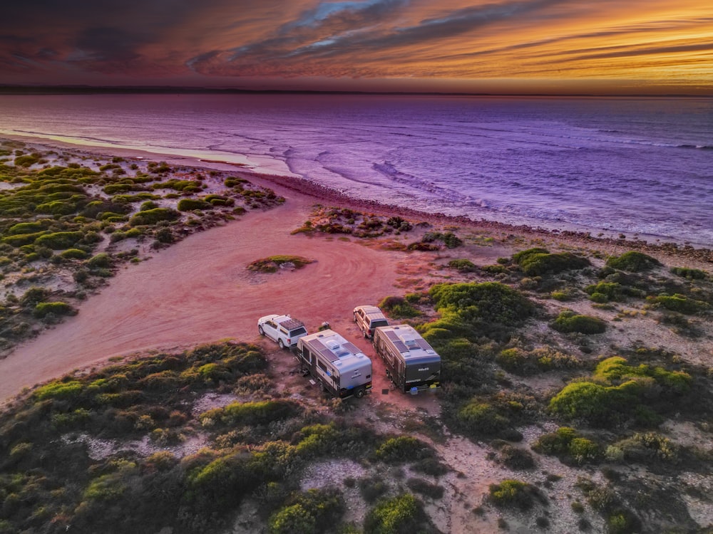 a couple of trucks parked on top of a sandy beach