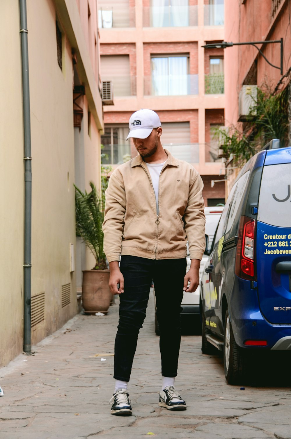 A man walking down a street next to a blue car photo – Free Morocco Image  on Unsplash