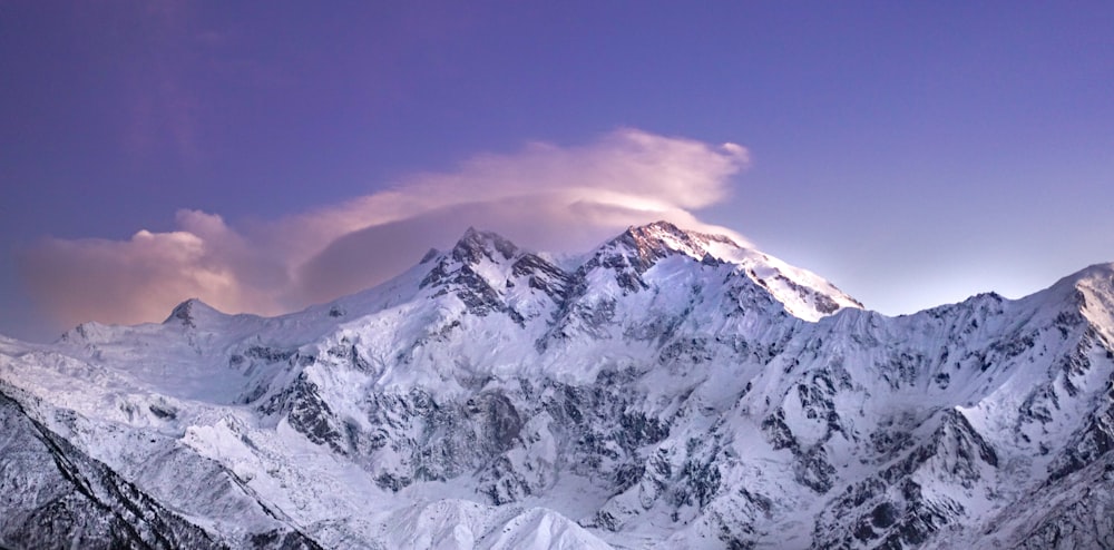 a snow covered mountain range under a purple sky