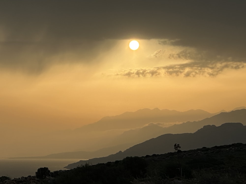 the sun is setting over a mountain range