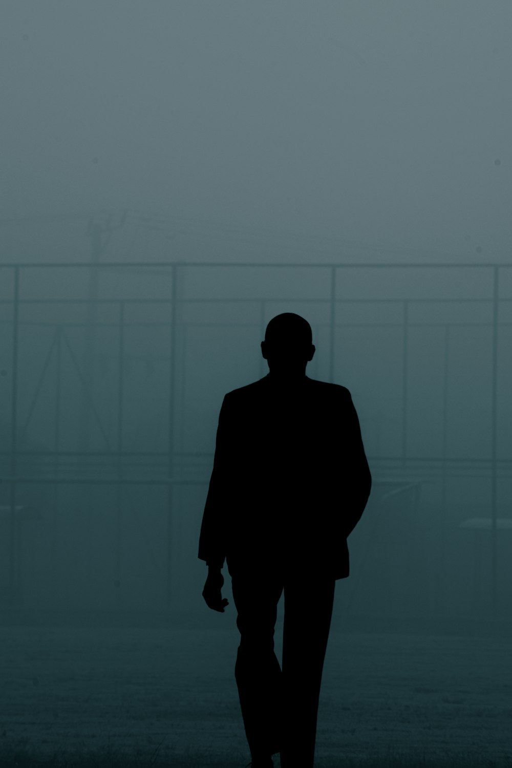 a silhouette of a man walking in the fog