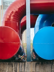 a large red and blue pipe sitting on top of a cement wall