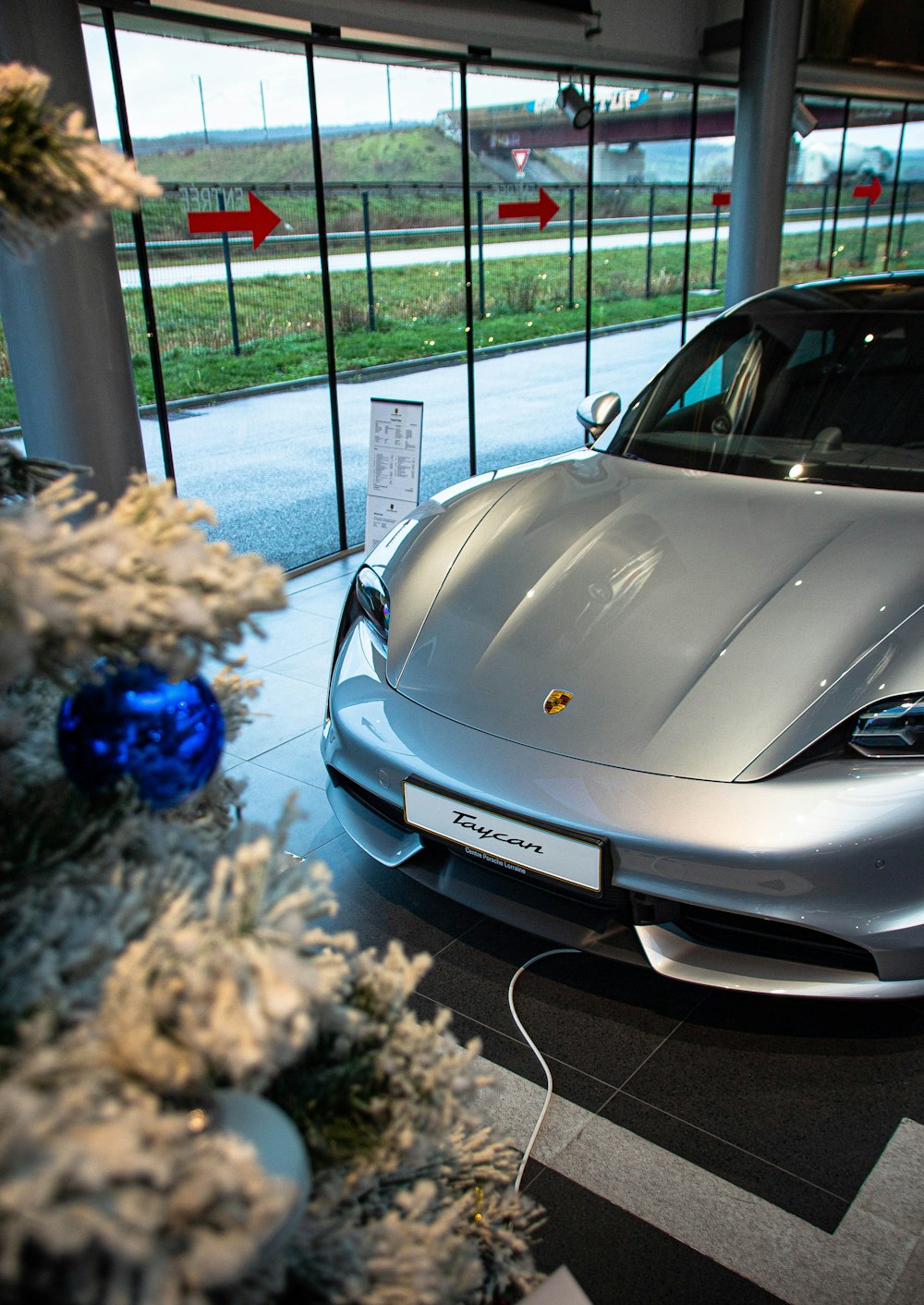 a silver sports car in a showroom next to a christmas tree