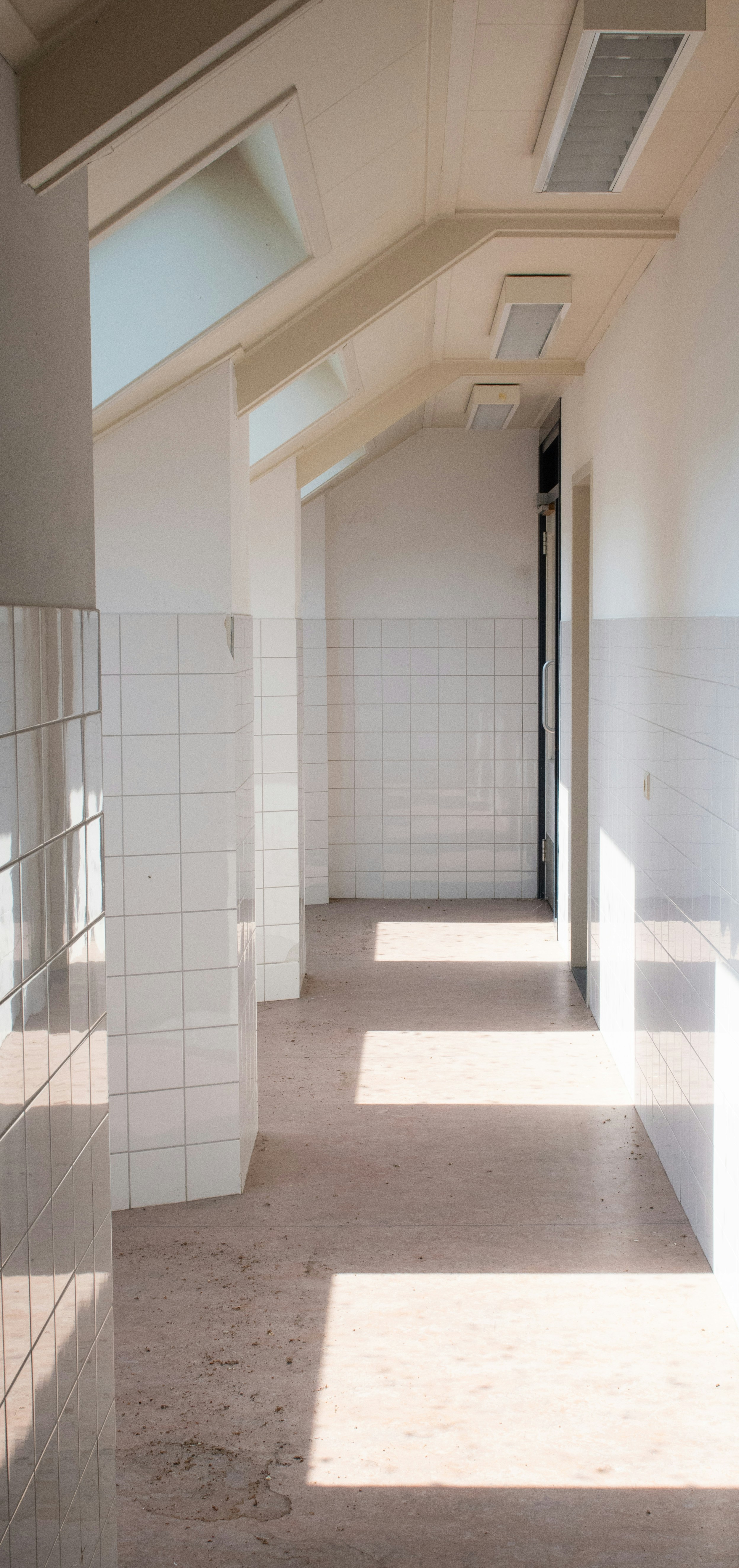 um longo corredor com paredes de azulejos e uma claraboia