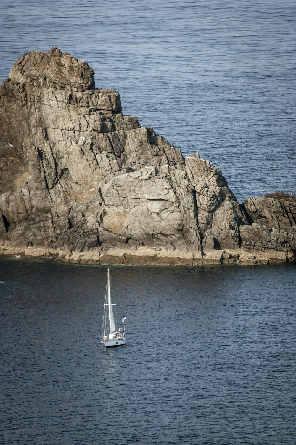 a sailboat in a body of water near a large rock
