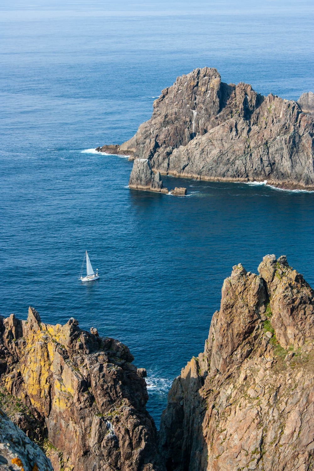 a sailboat in the ocean near some rocks