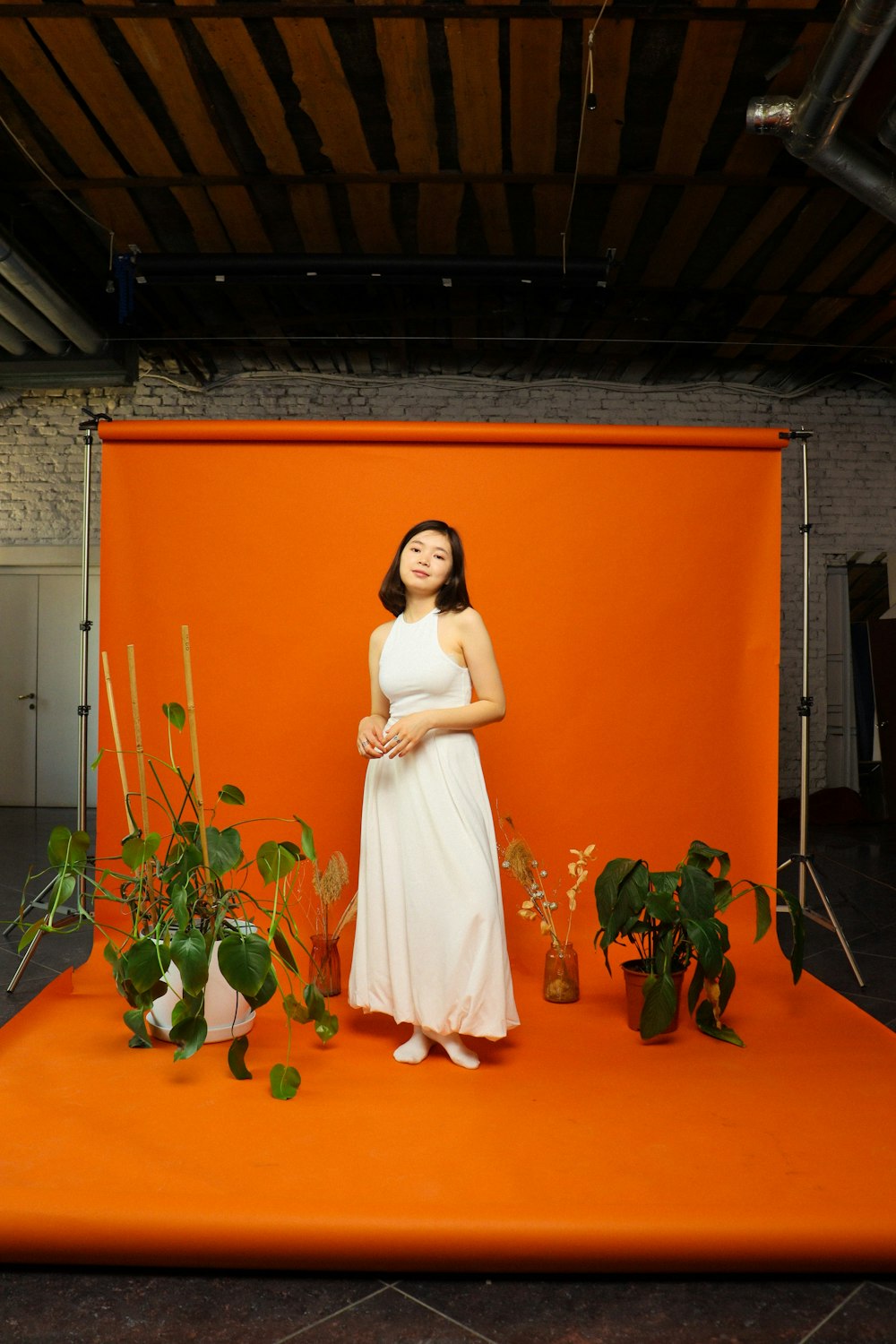 a woman in a white dress standing in front of an orange backdrop