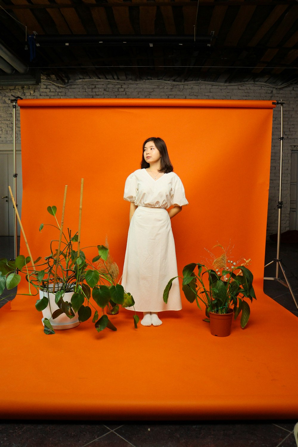 a woman in a white dress standing in front of an orange backdrop