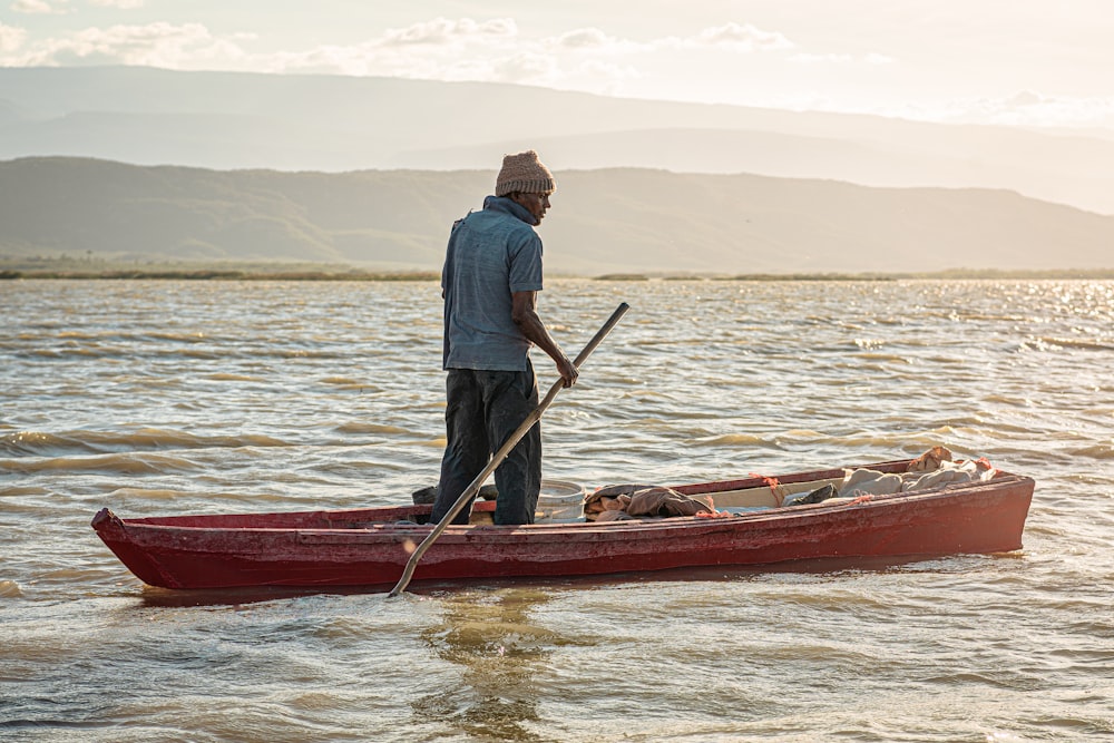 a man standing in a red canoe with a dog