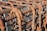 A close-up view of a grid structure made from rusted steel rebar, with each bar intricately twisted and held together by looping wire ties. The rusty texture and patina are clearly visible, indicating weathering and age.