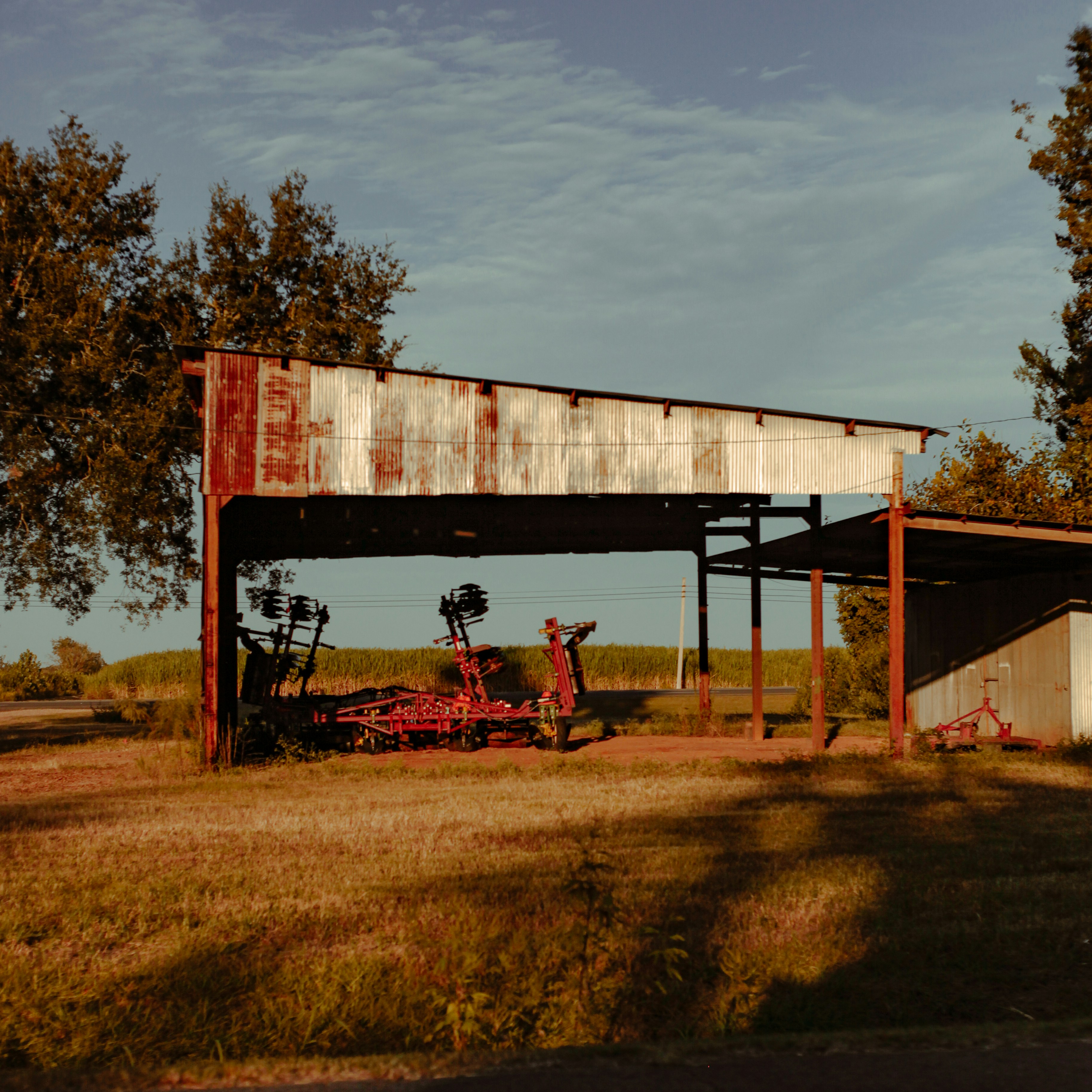 a tractor parked under a covered structure in a field