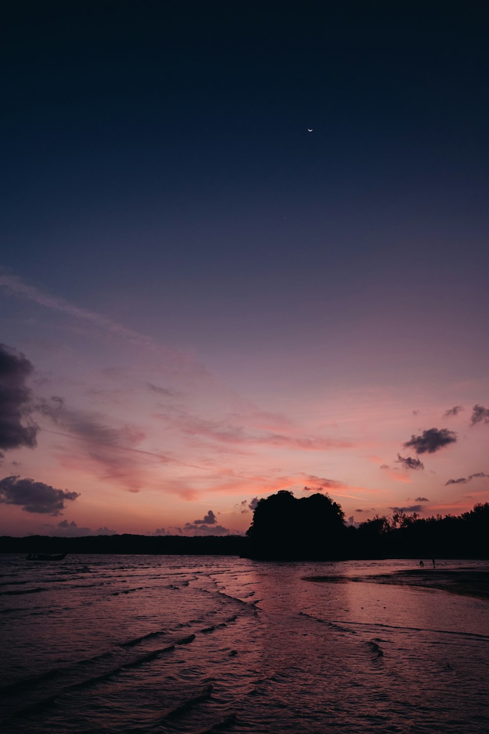 the sun is setting over the water at the beach