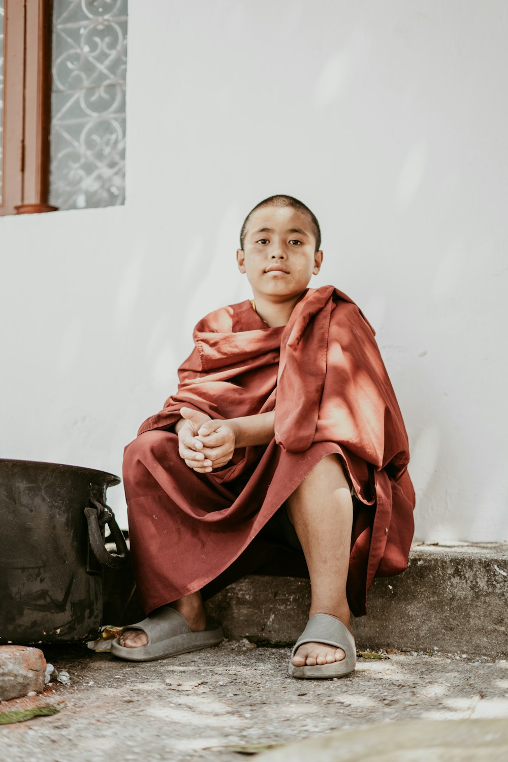 a man sitting on the ground wearing a red robe