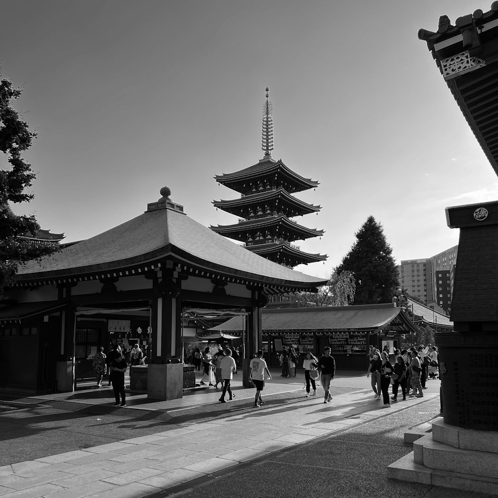 a black and white photo of people walking in front of a pagoda