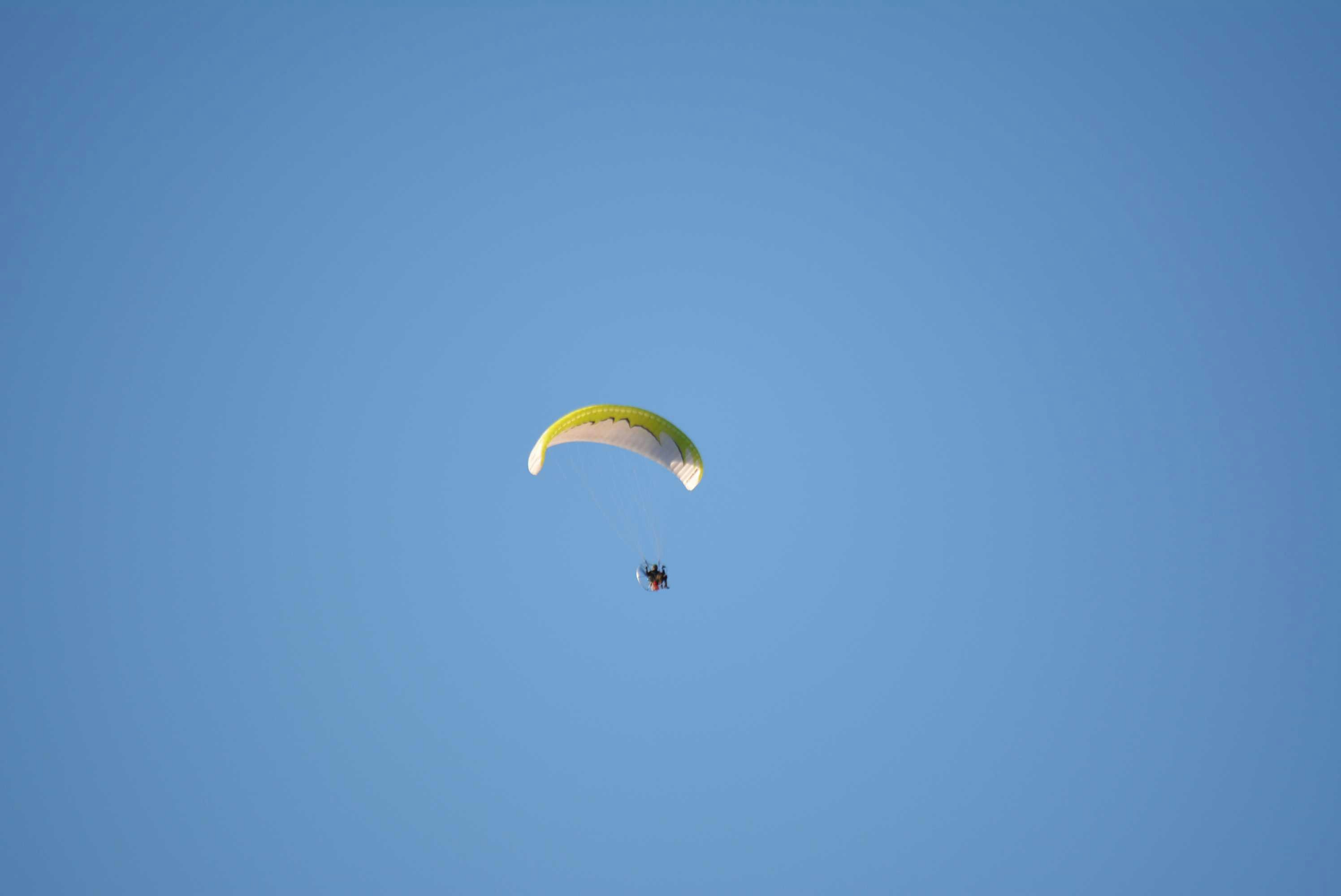 a parasailer is flying high in the blue sky
