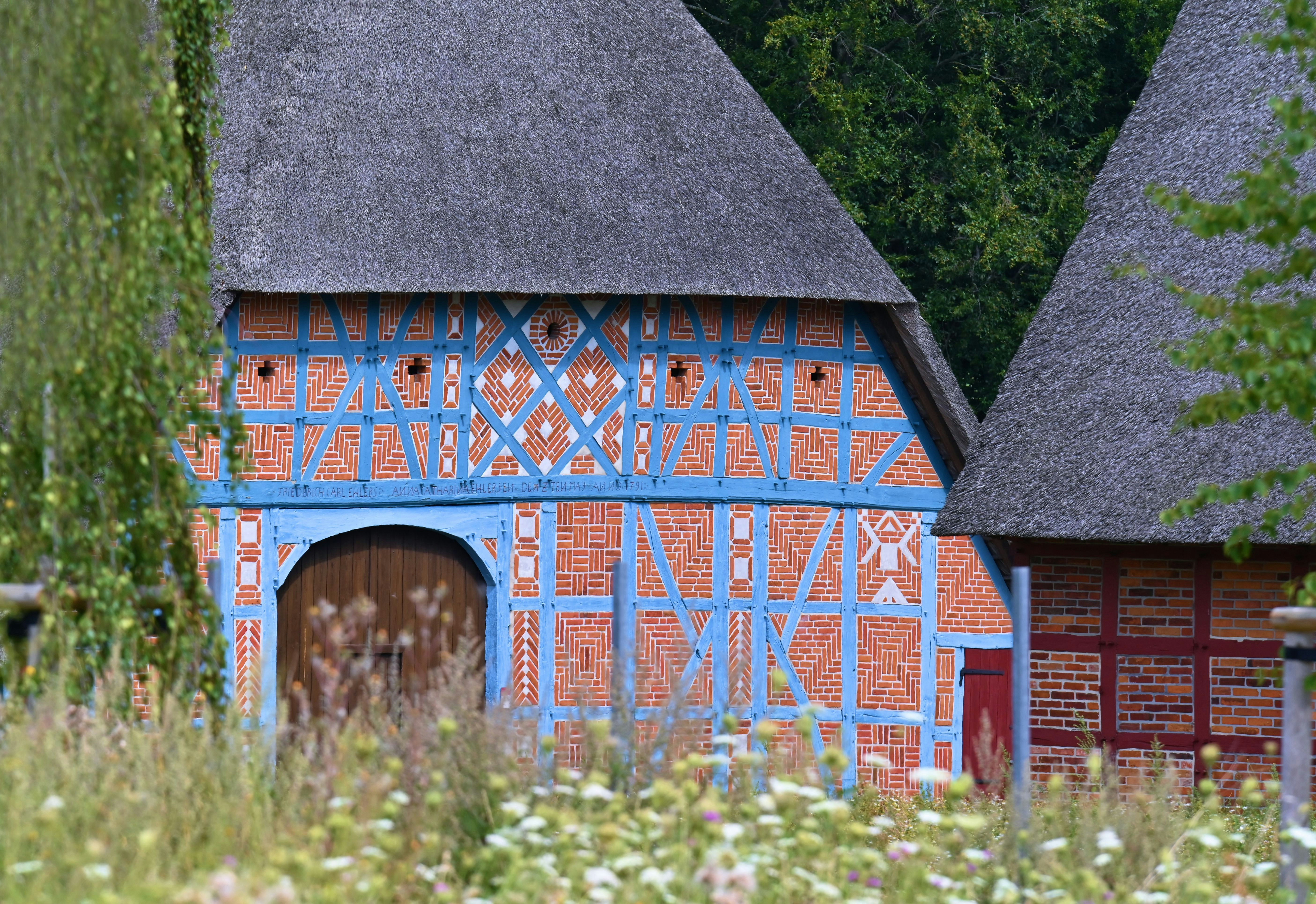 a blue and red building with a thatched roof