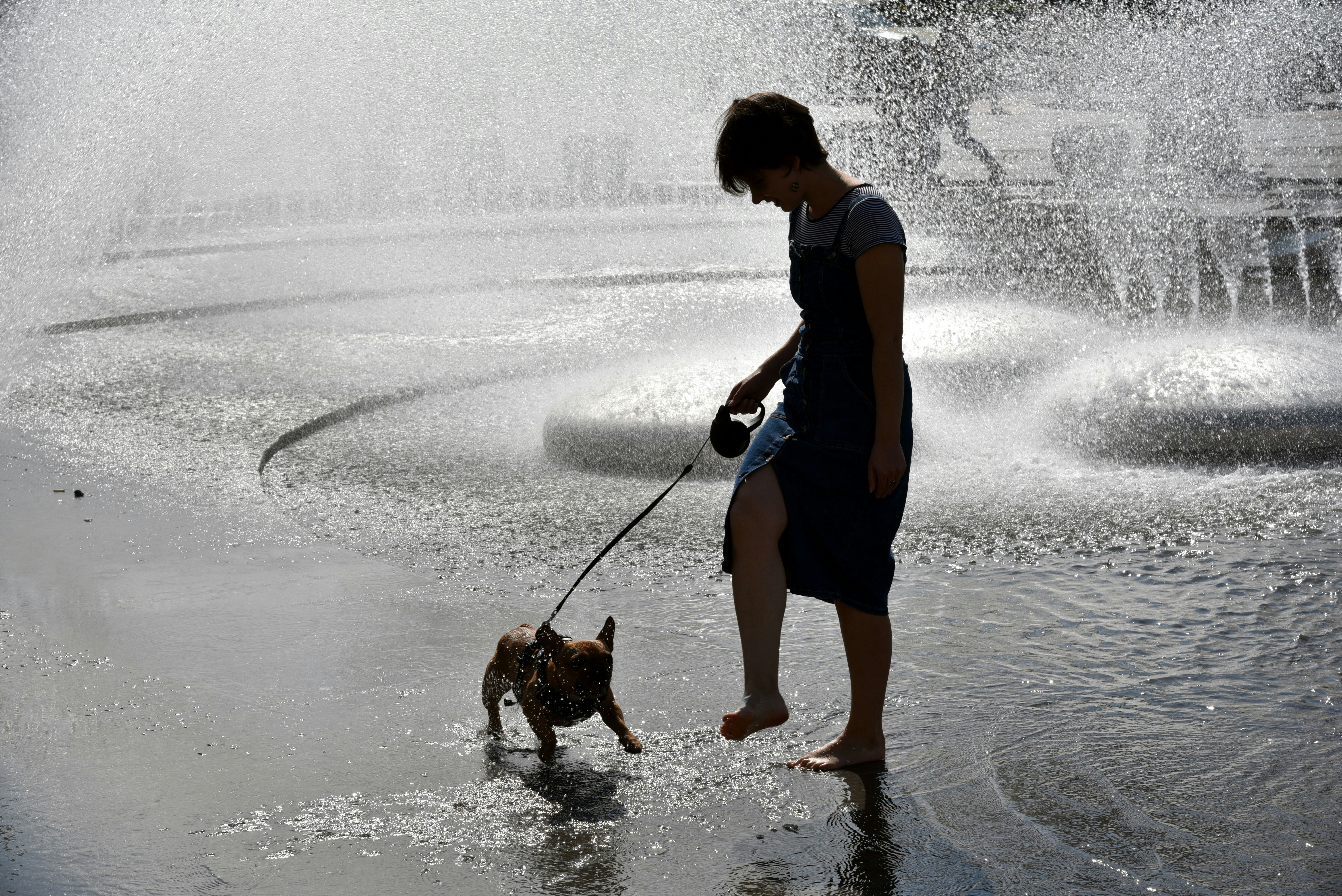 a woman is walking her dog through a fountain