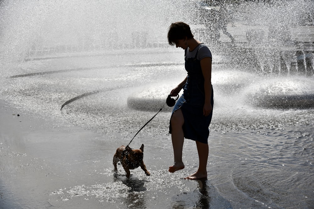 a woman is walking her dog through a fountain