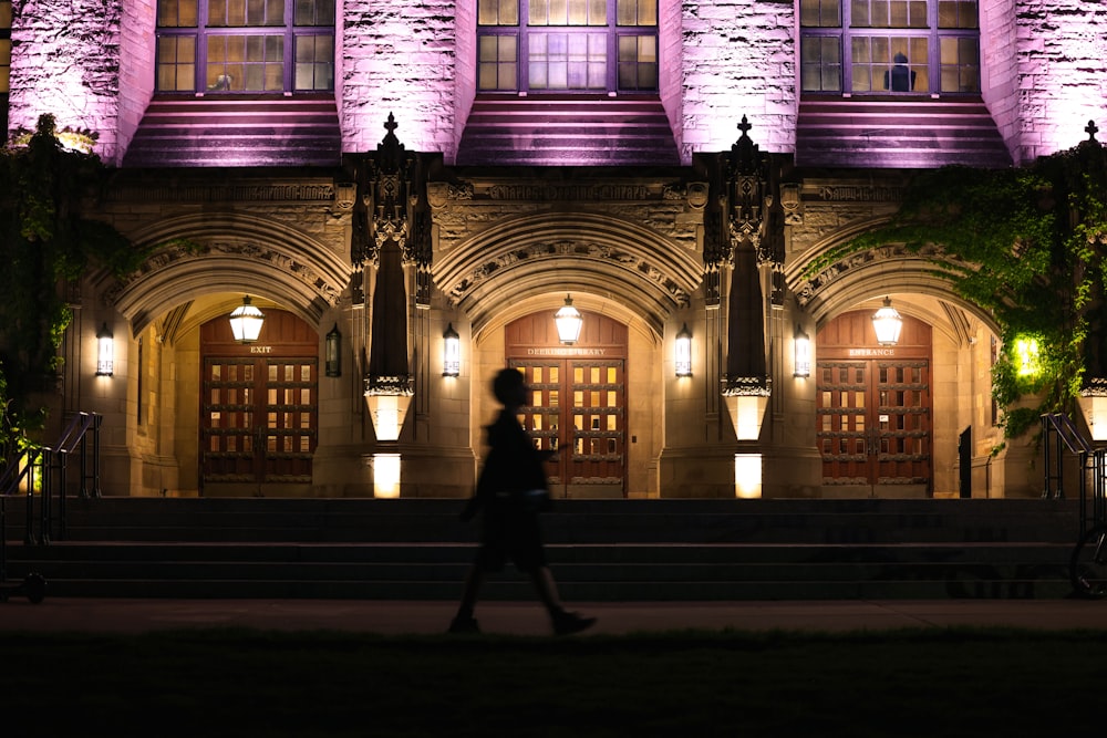 a person walking in front of a building at night