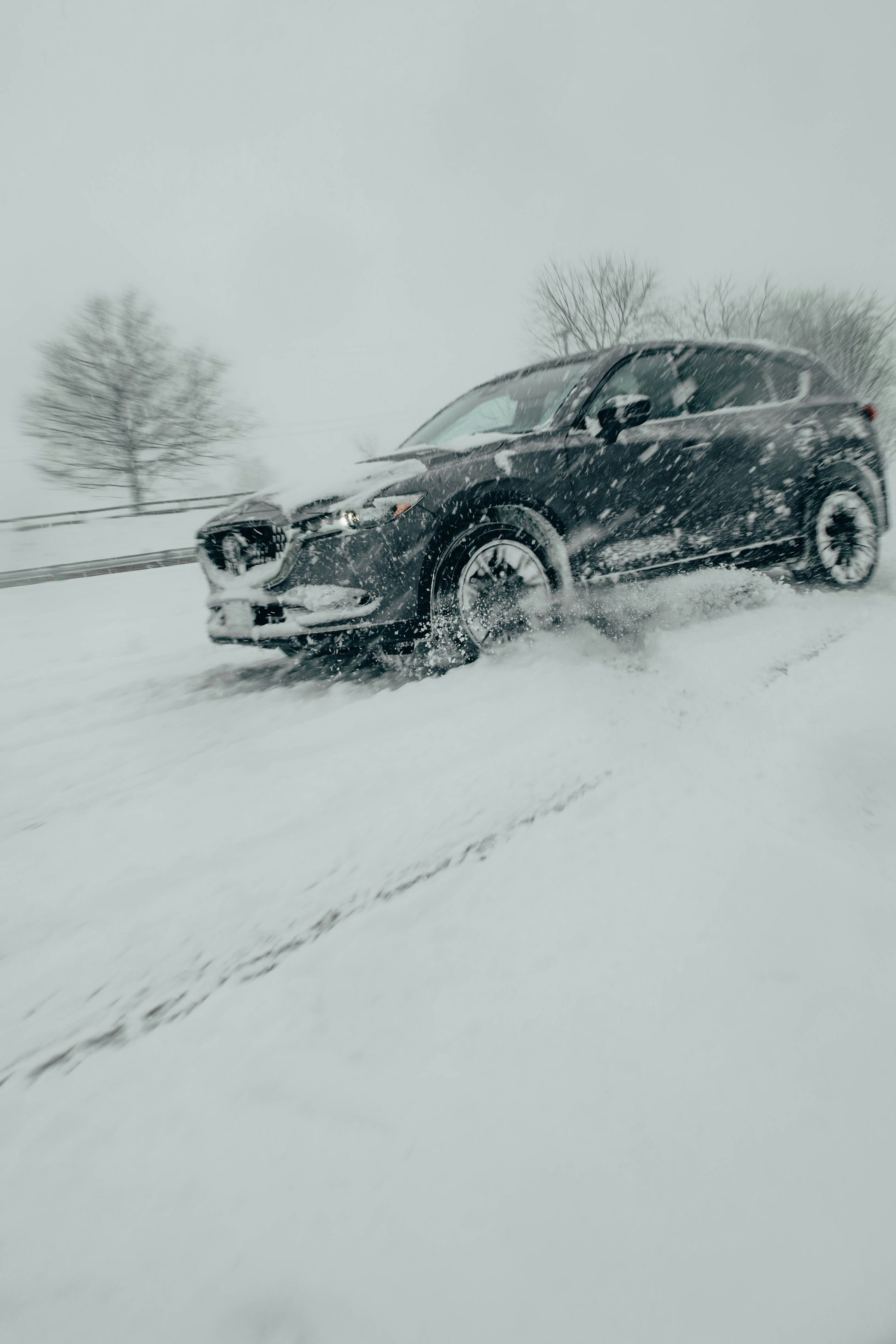 a black car driving down a snow covered road