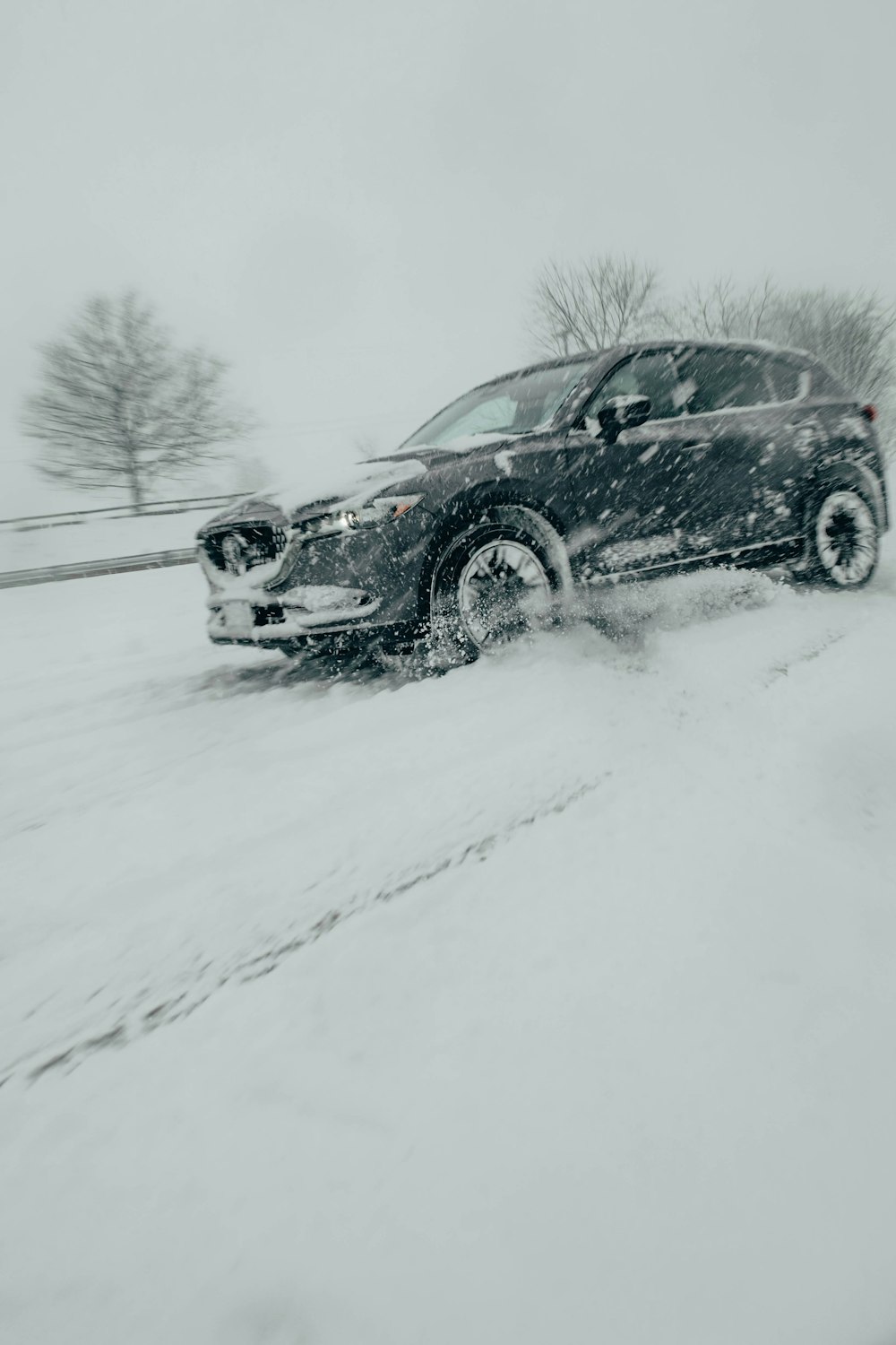 ein schwarzes Auto, das eine schneebedeckte Straße hinunterfährt