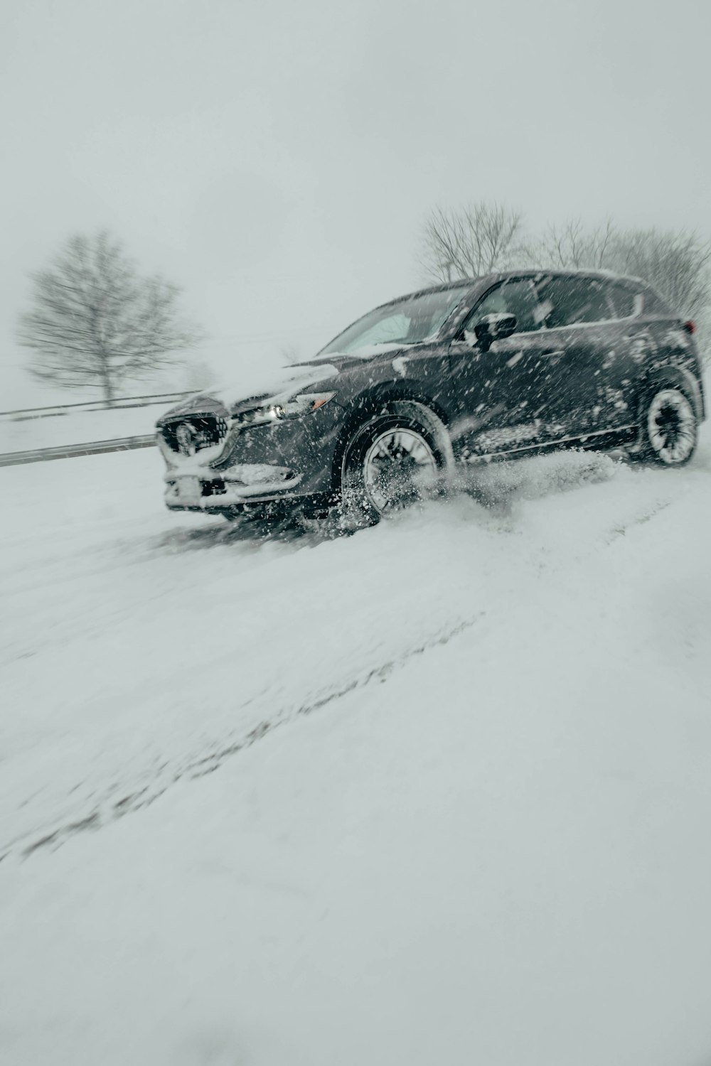 a black car driving down a snow covered road