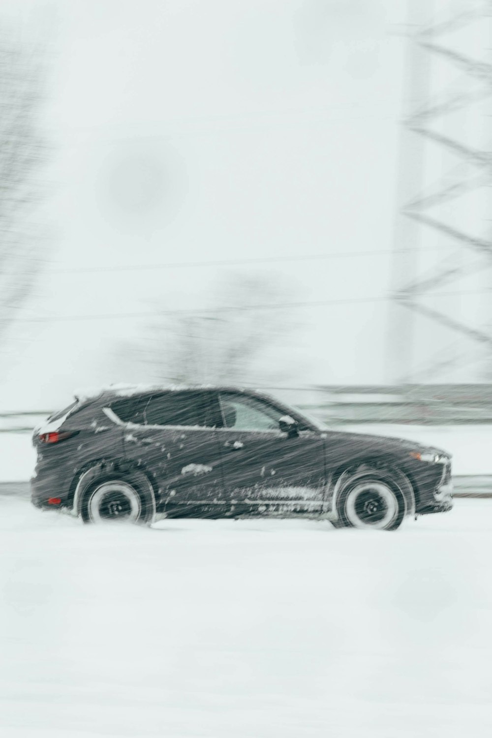 um carro preto dirigindo por uma estrada nevada