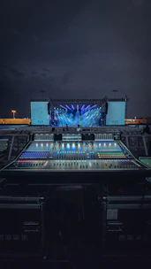 A professional sound system setup at an outdoor event with stage lighting.
