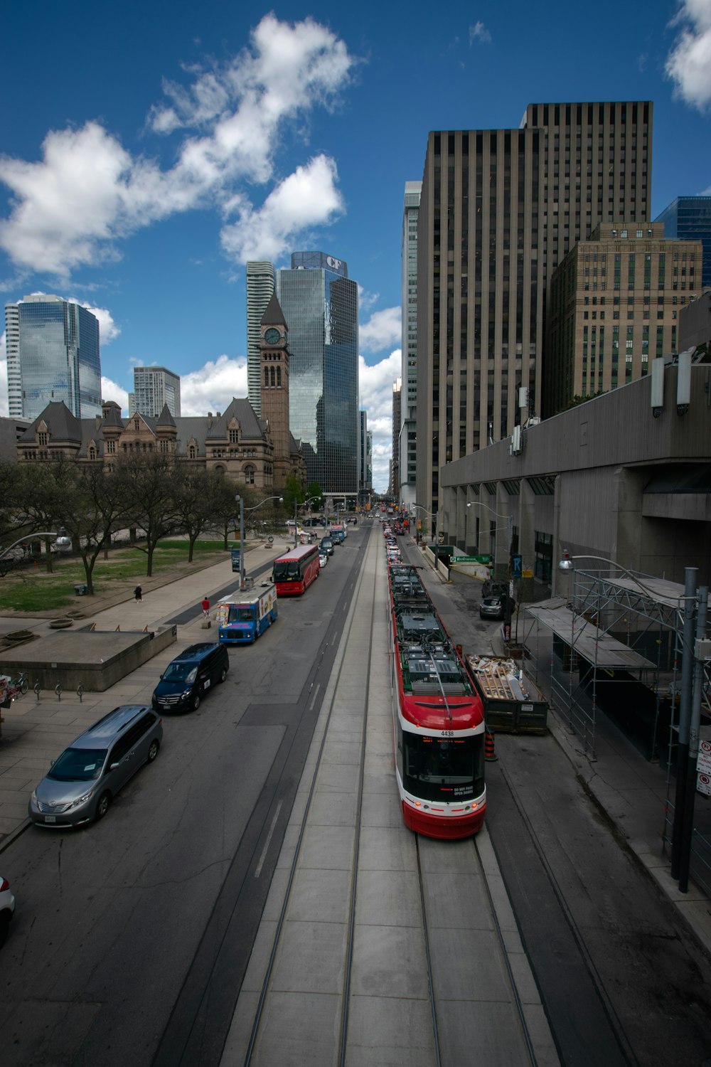 a red and white bus traveling down a street next to tall buildings